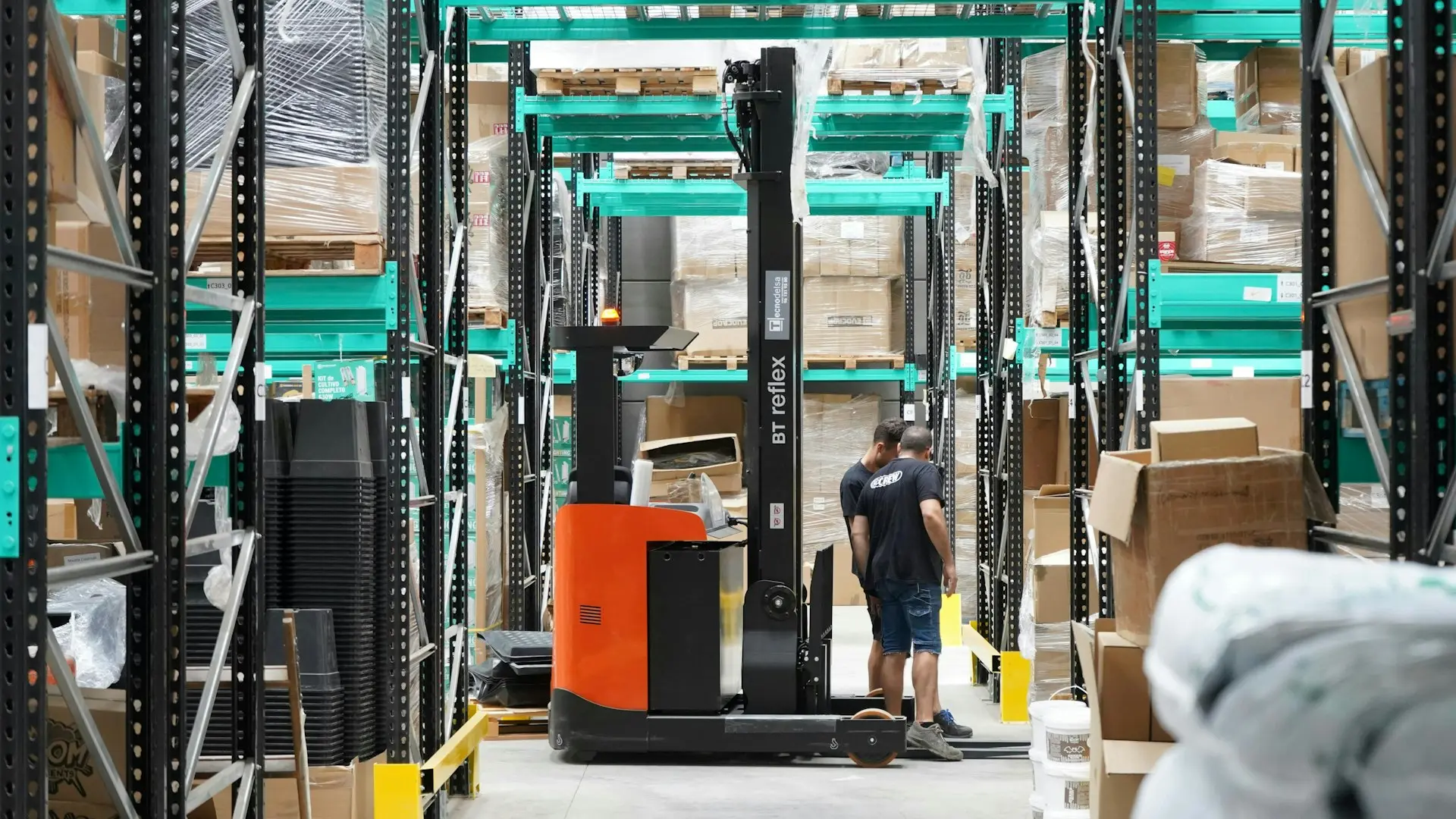 A man standing in a warehouse with a fork lift